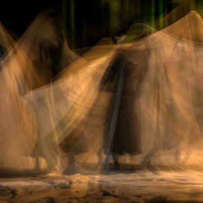 Blurred image showing a blur of white sheets with a black backgrounf